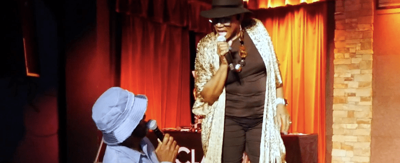 Two performers singing on stage with microphones.
